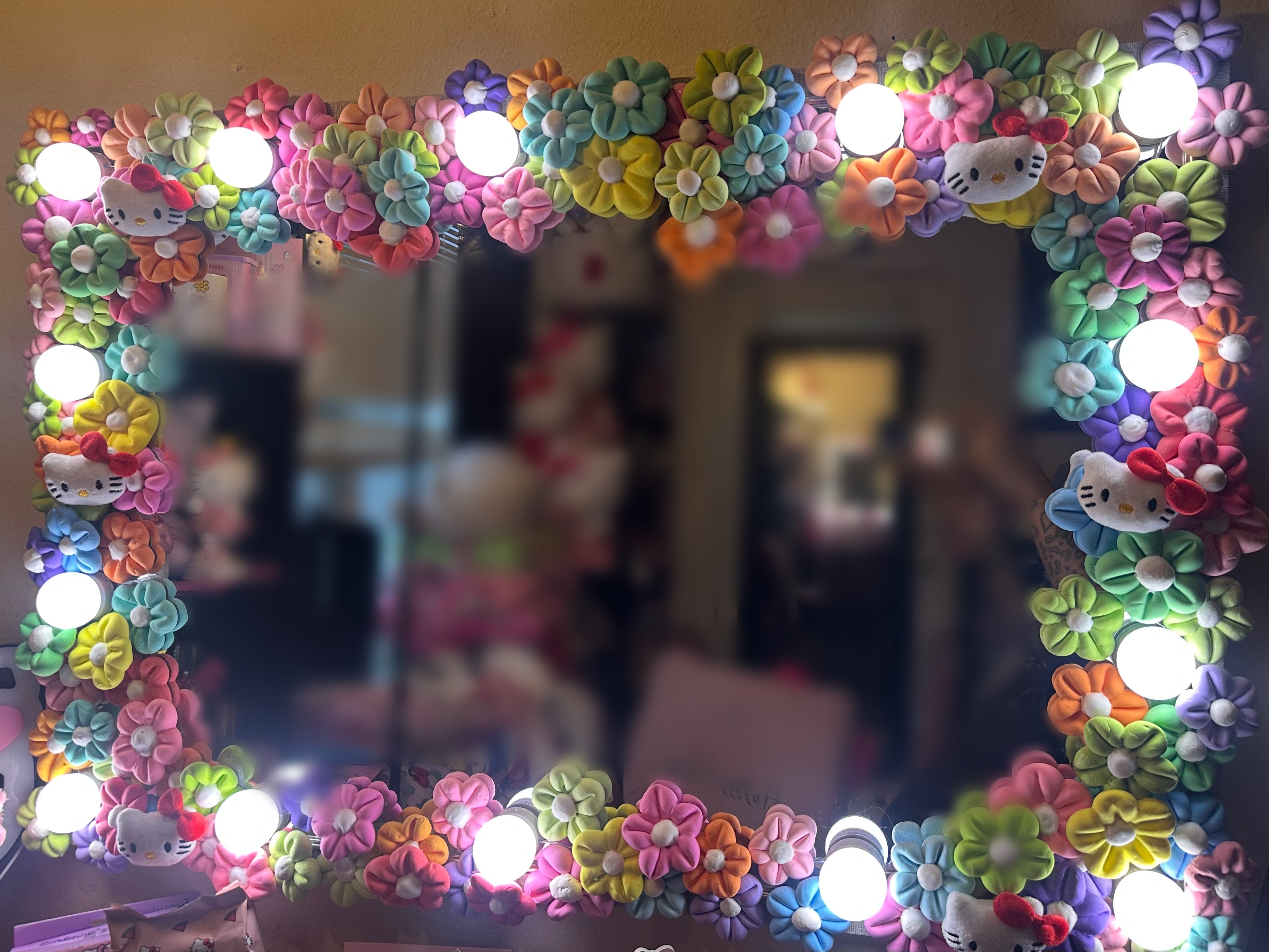 Decorative mirror with colorful floral and Hello Kitty designs, illuminated by multiple lights.